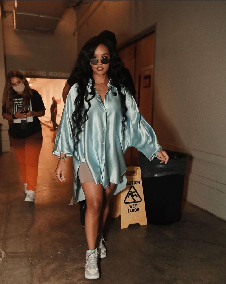 a woman walking down a hallway wearing sunglasses