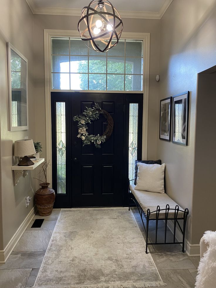 a black door with a wreath on it and a white bench in front of it