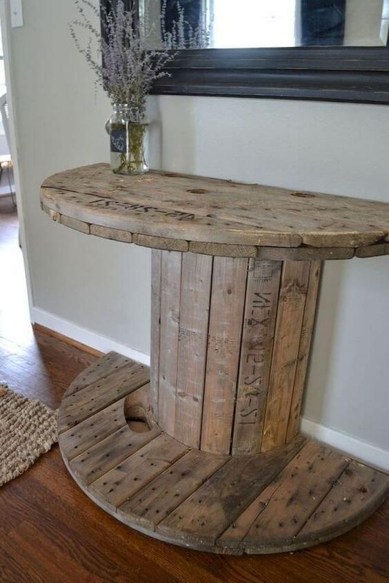 a round wooden table sitting on top of a hard wood floor next to a mirror