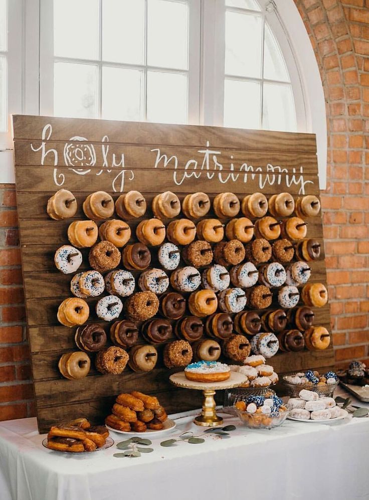 a table topped with lots of donuts next to a sign