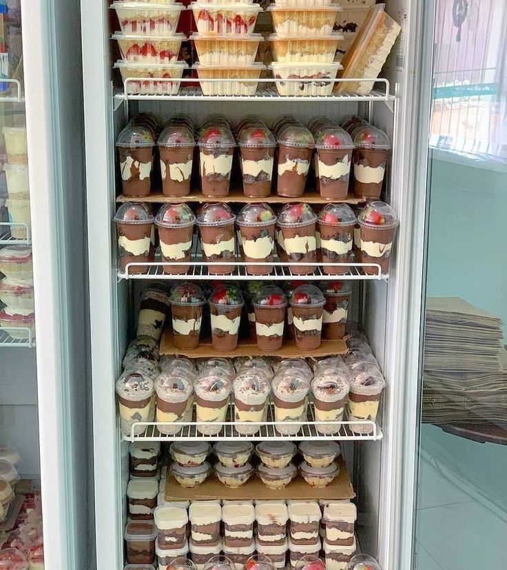 a refrigerator filled with lots of cupcakes and other desserts on shelves next to each other