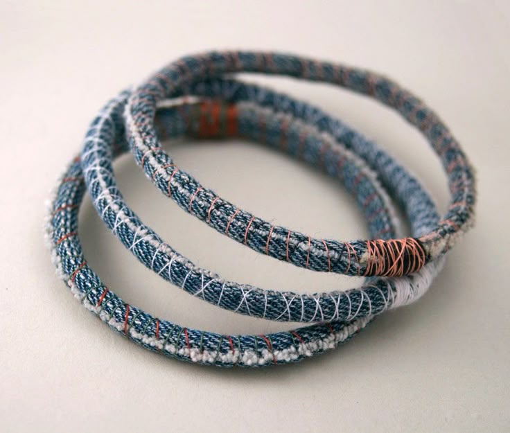 three blue and white bracelets with red beads on each one side, set against a white background