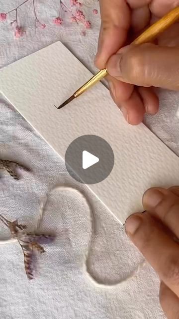 someone is drawing something on paper with a pencil and watercolors in their hands