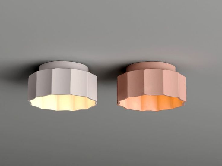 two lights are hanging from the ceiling in an empty room, one is white and the other is pink