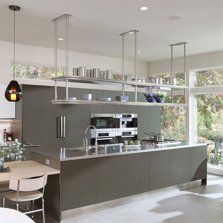 a modern kitchen with stainless steel appliances and counter tops, along with dining room furniture