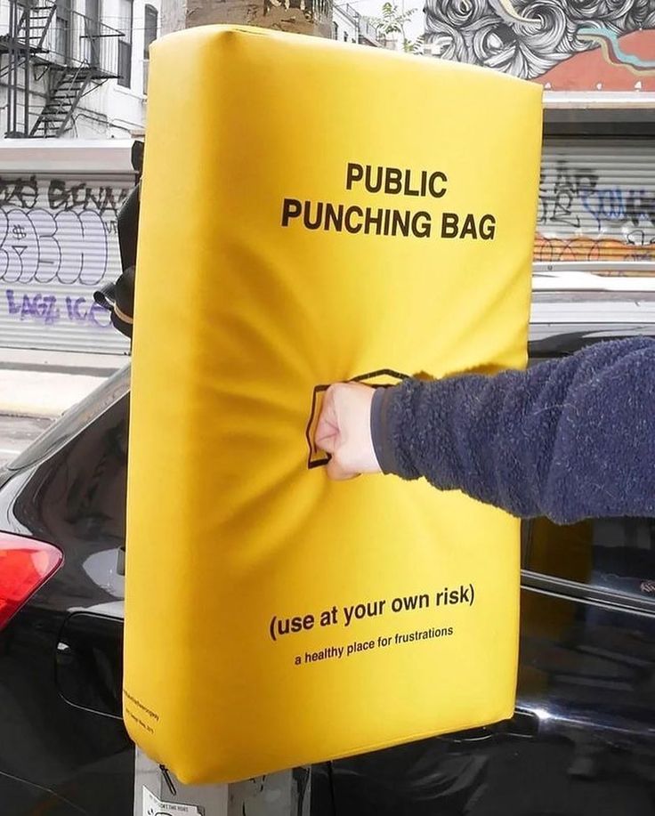 a person holding onto a public punching bag attached to a pole in front of a car