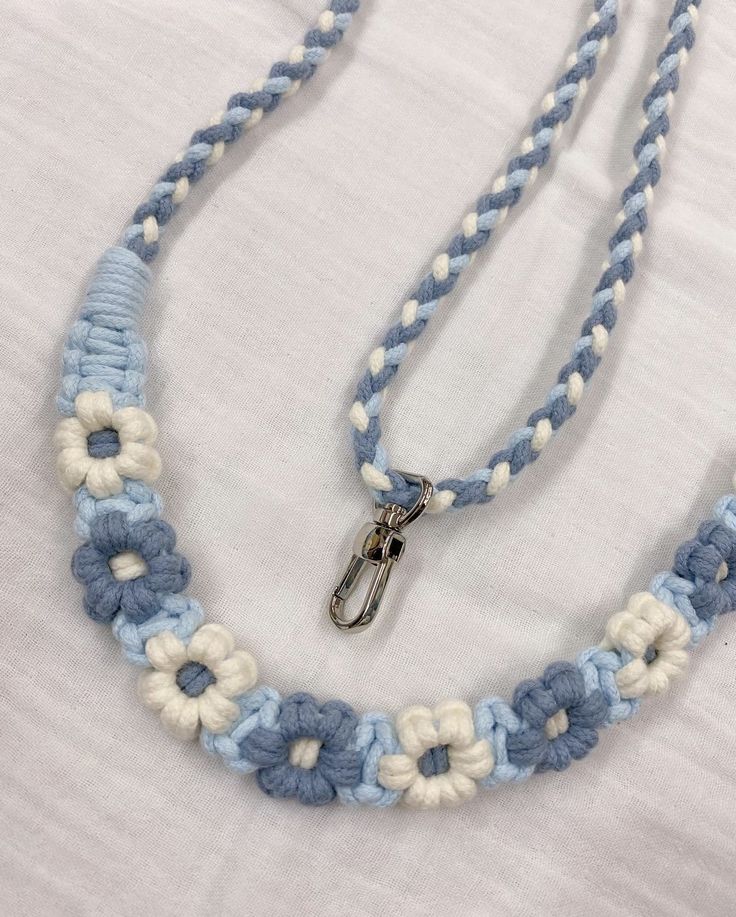 a blue and white crocheted necklace on a white sheet with a pair of scissors