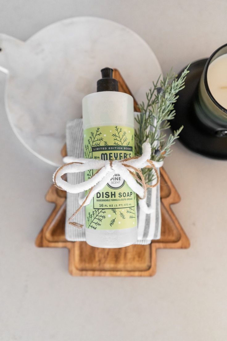 a dish towel and soap sitting on top of a wooden tray next to a candle