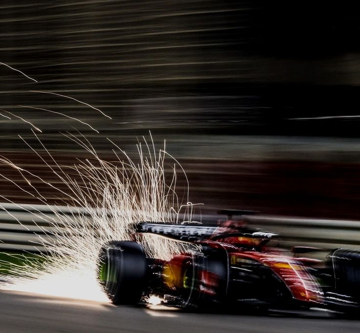 a red and yellow race car driving down a track with sparks coming out of it