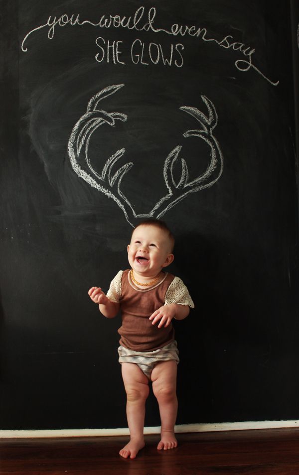 a baby sitting in front of a blackboard with writing on it