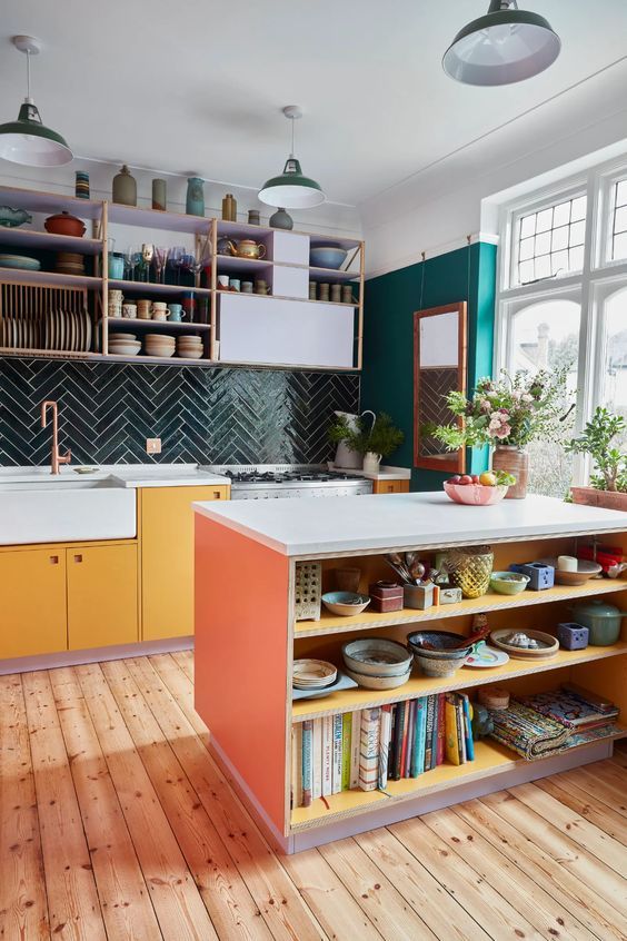 a kitchen with yellow cabinets and white counter tops next to a window filled with potted plants