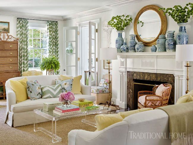 a living room filled with furniture and a fire place in front of a mirror on the wall