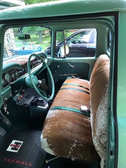 the interior of an old green truck with leather seat covers and cowhide on it