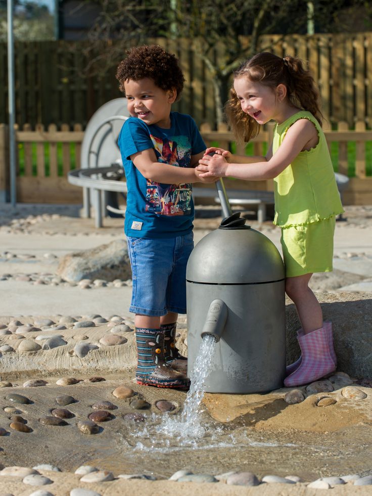 two young children playing in a water fountain