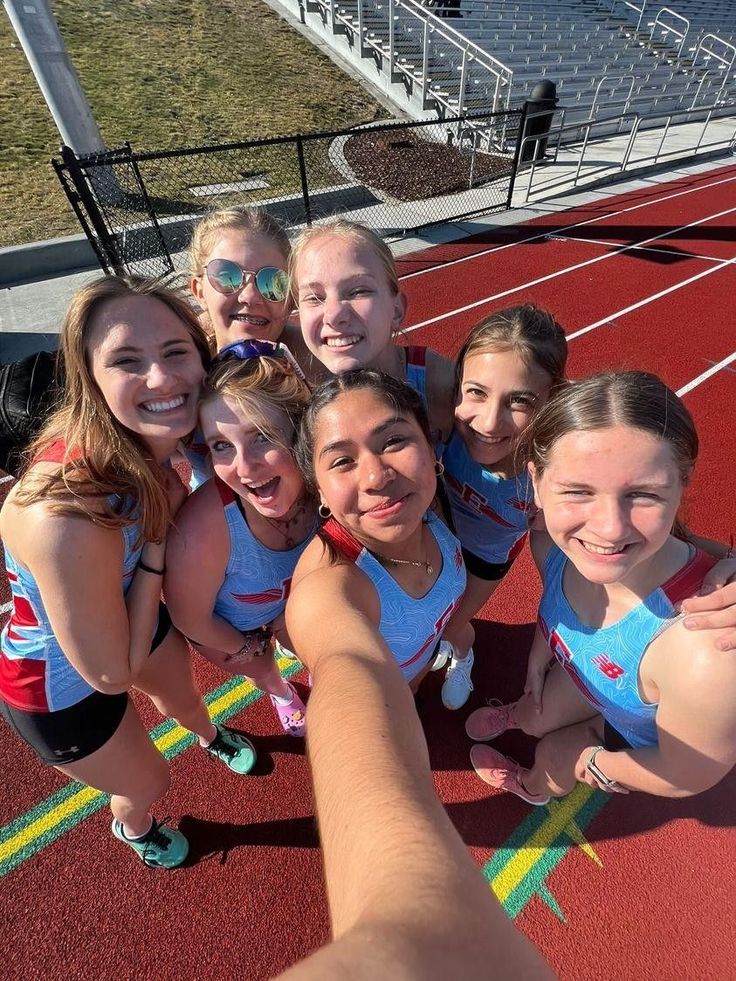 a group of young women standing on top of a red track next to each other