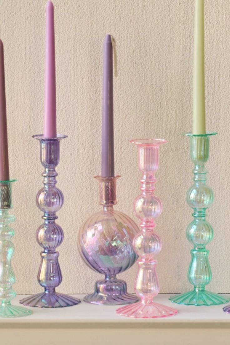 there are many different colored candles on the shelf