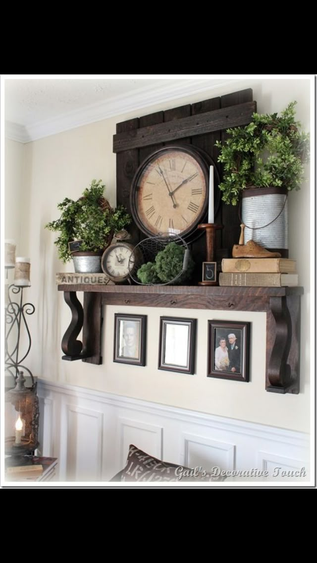 an old clock is sitting on top of a shelf with pictures and other things around it