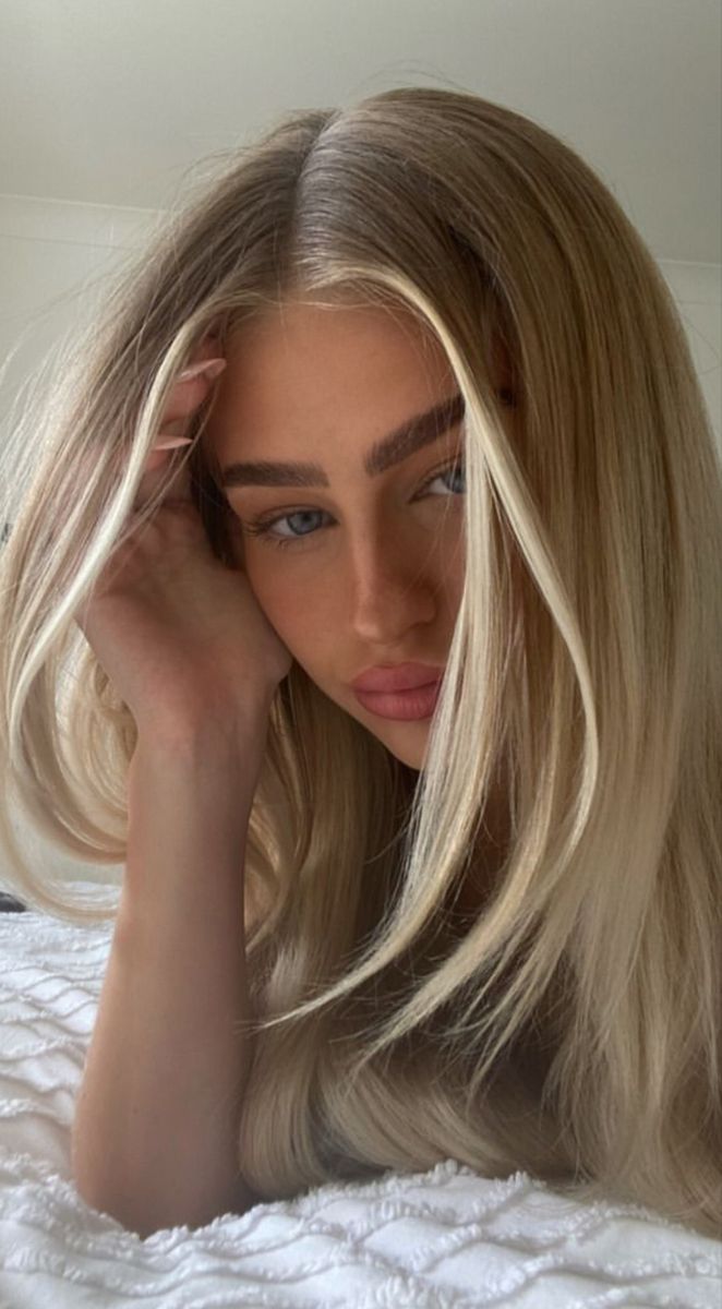 a woman laying on top of a bed with blonde hair