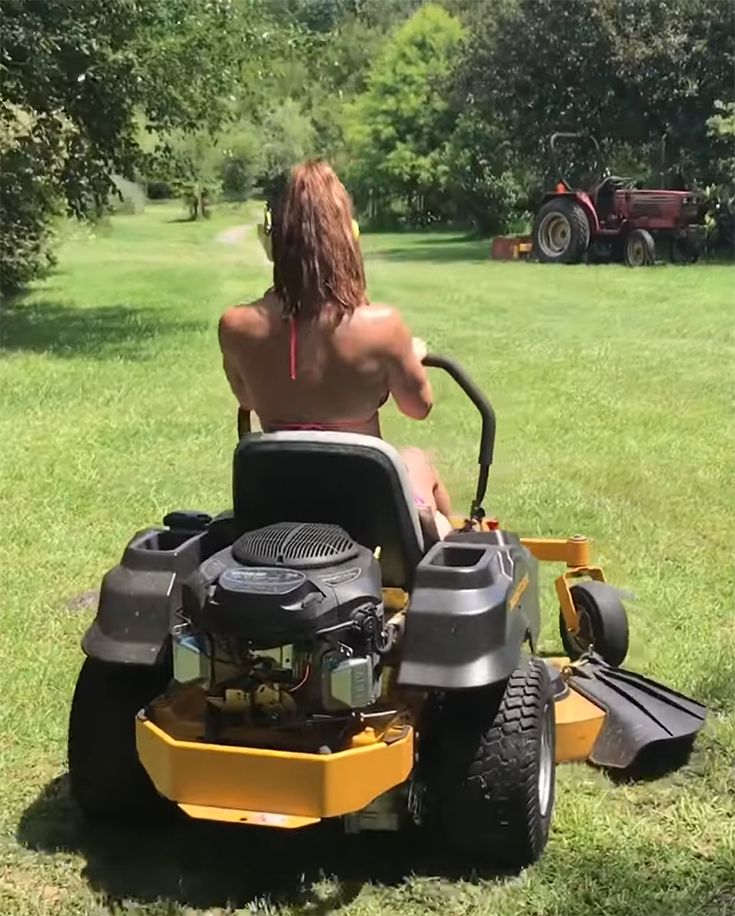 a man riding on the back of a yellow lawn mower