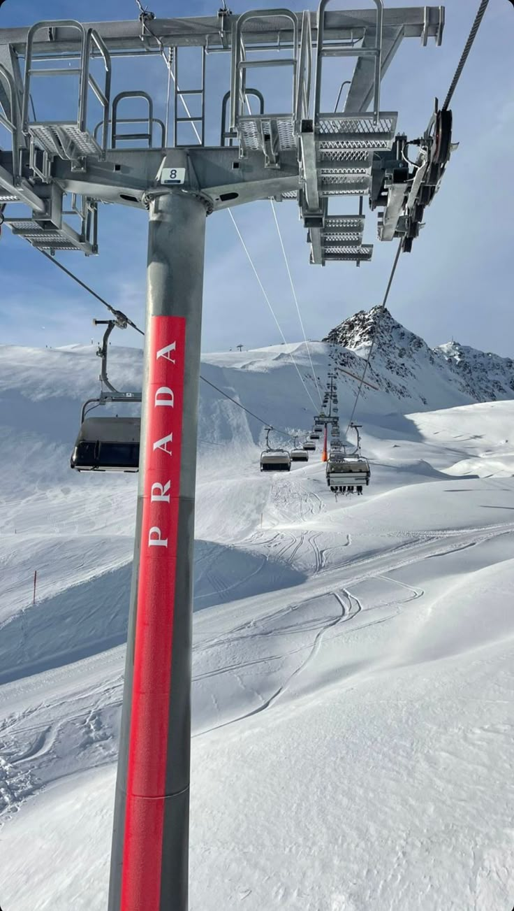 a red ski lift going up the side of a snow covered mountain