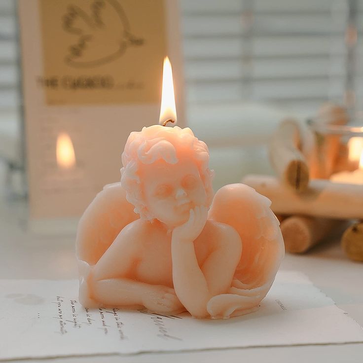 a candle sitting on top of an open book next to a teddy bear figurine