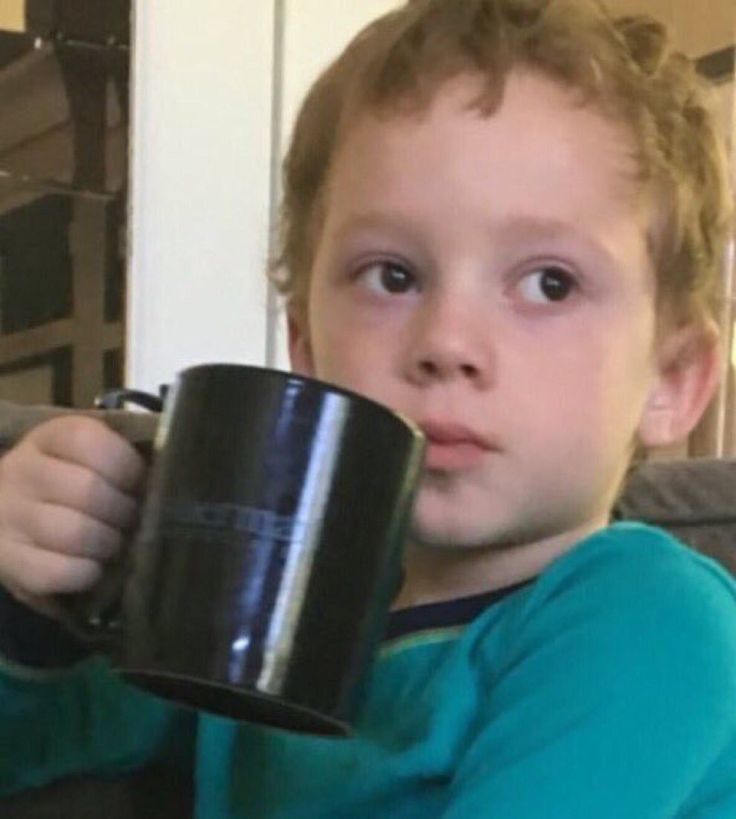 a young boy holding a black coffee mug