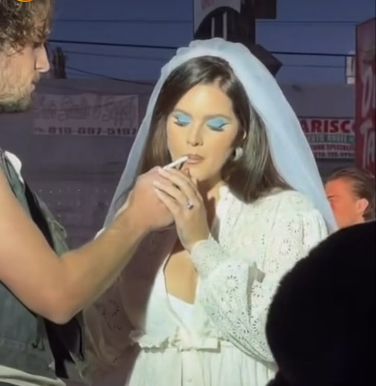 a man and woman are dressed up in wedding attire, one is brushing the other's teeth