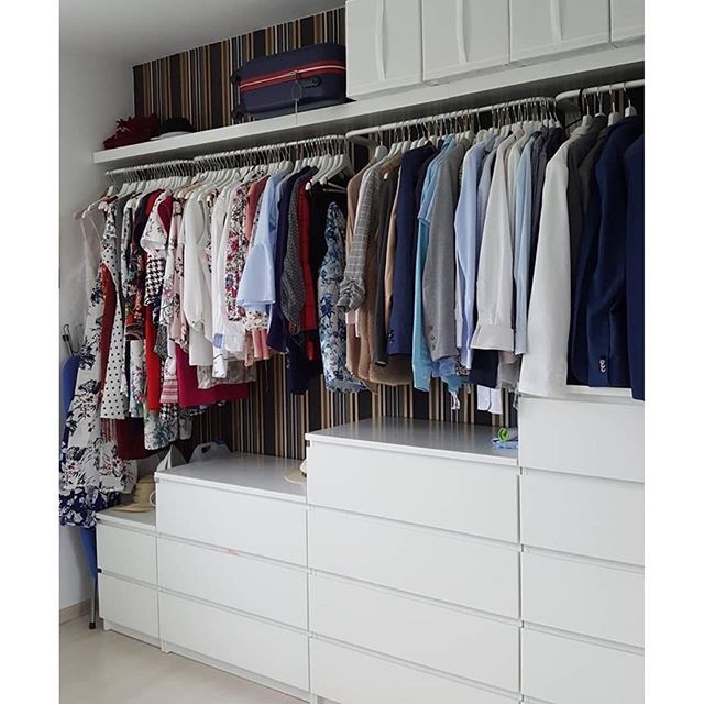 an organized closet with white drawers and clothes on hangers