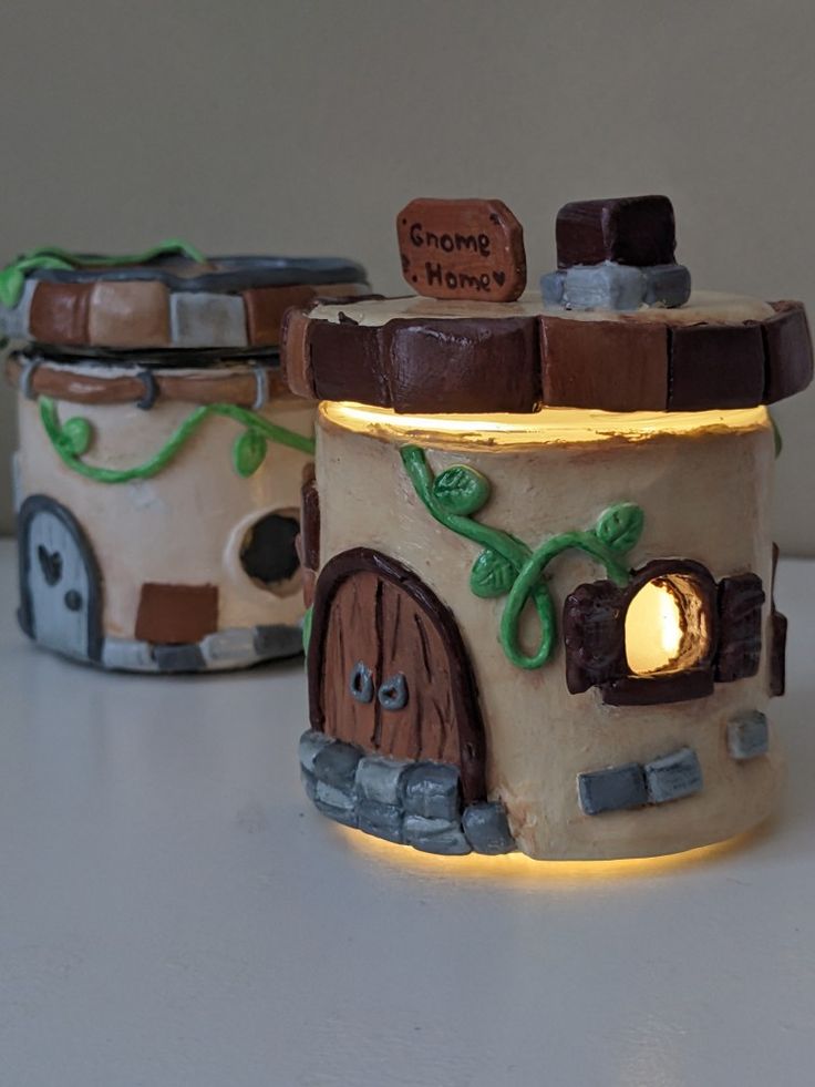 two small clay houses with lights on them