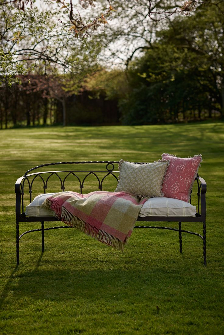 a park bench with pillows on it in the grass