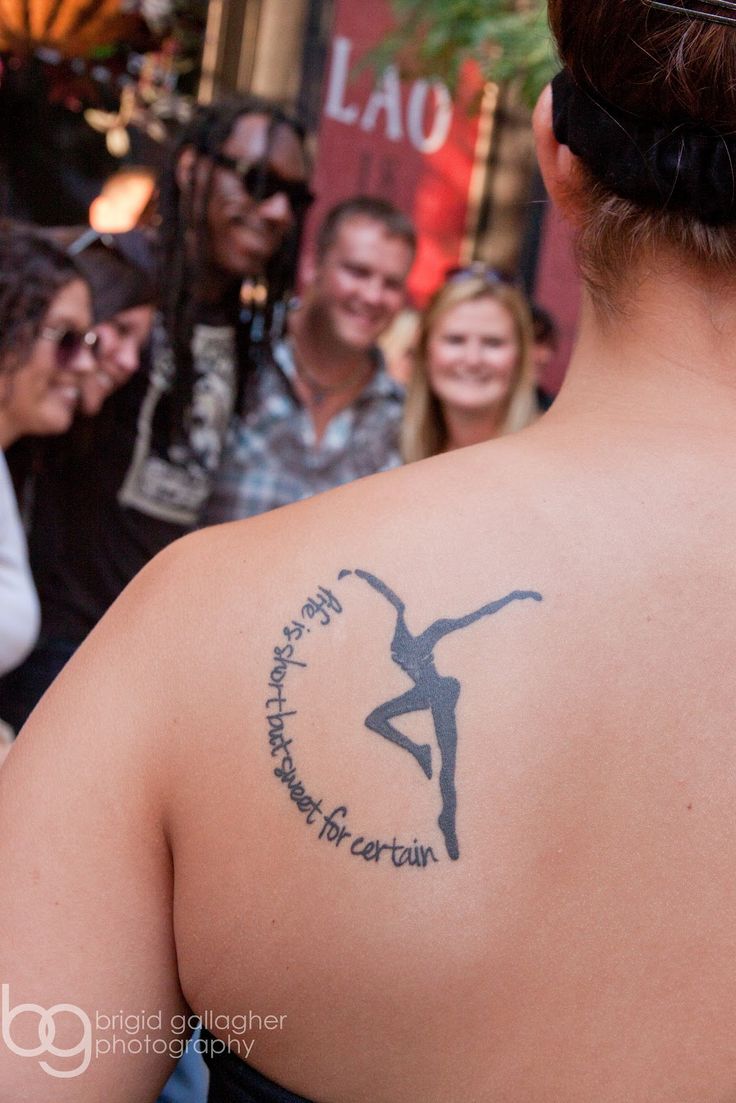 a woman with a tattoo on her back is standing in front of some other people