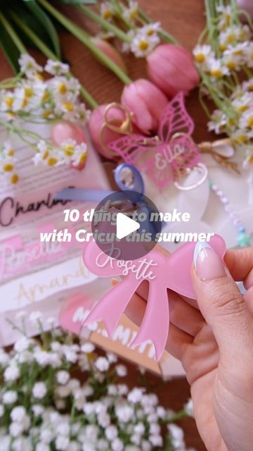 a person holding a pink ribbon in front of some flowers and other items on a table