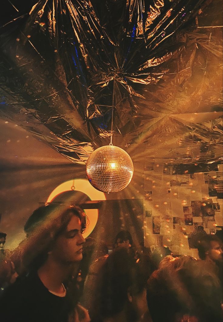 a disco ball hanging from the ceiling in front of people