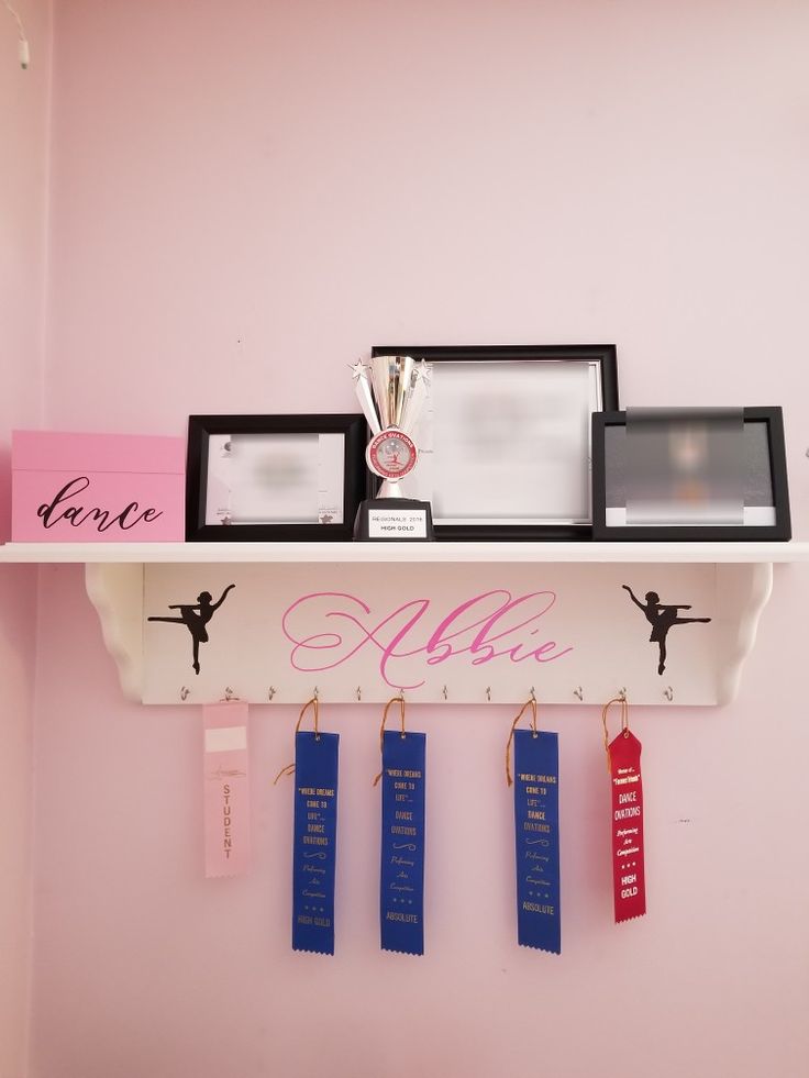 there is a shelf with medals on it that has ribbons hanging from the top and two plaques attached to the bottom