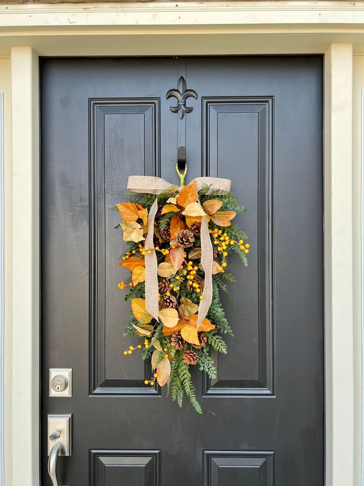 a wreath on the front door of a house decorated with autumn leaves and foliages