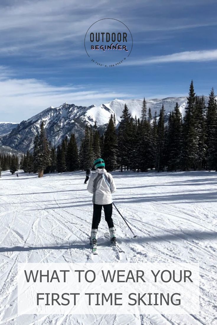 a person on skis standing in the snow with trees and mountains behind them text reads, what to wear your first time skiing