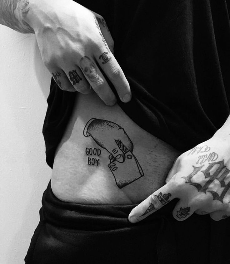 a person with tattoos on their stomach holding something in one hand and pointing to the other