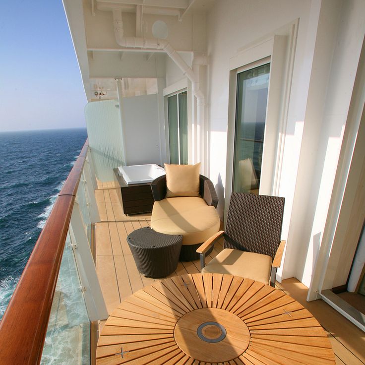 a balcony overlooking the ocean with chairs and an umbrella