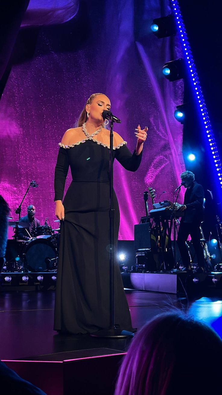 a woman standing on top of a stage in front of a microphone and other people