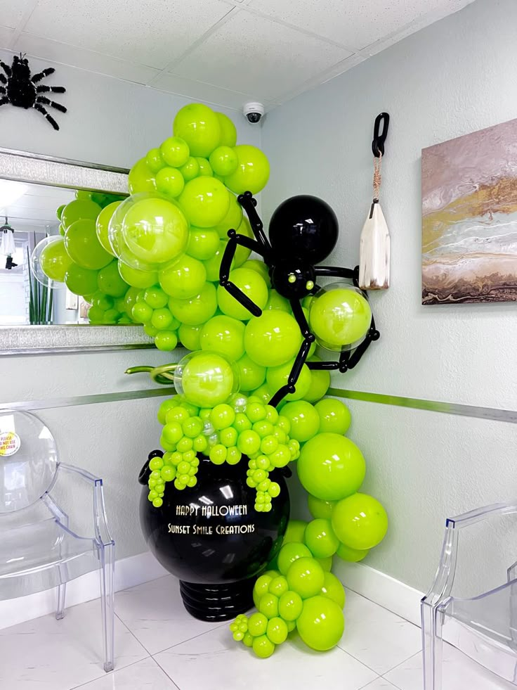 a vase filled with green balloons sitting on top of a white floor next to a mirror