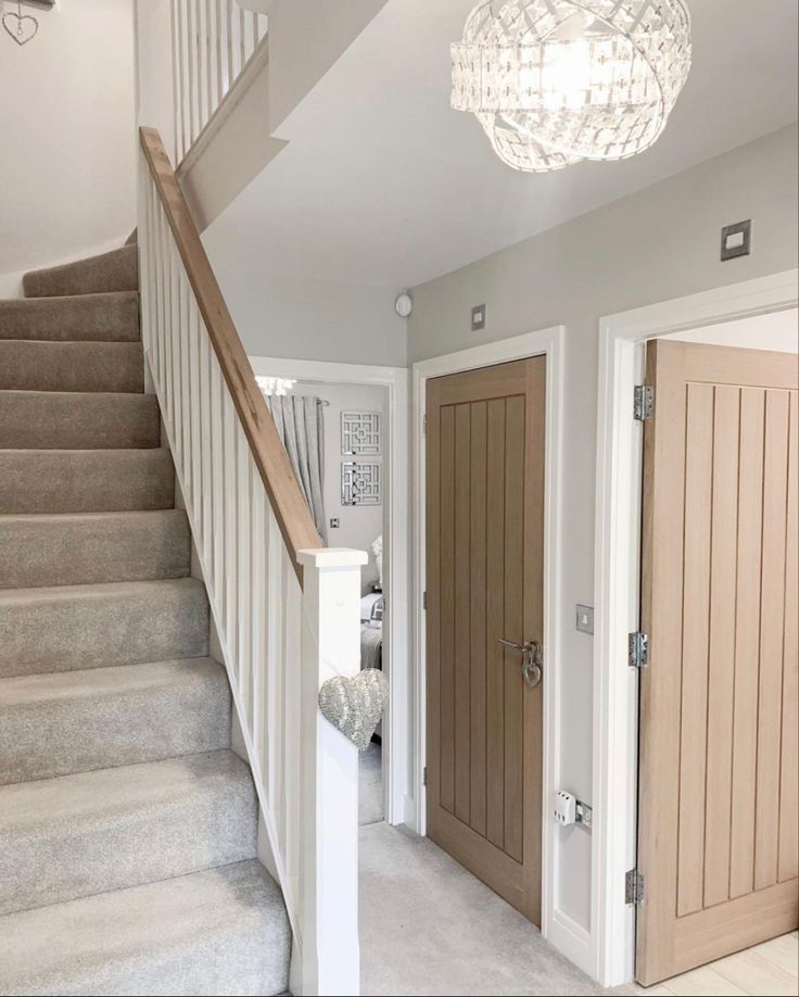 a staircase leading up to two doors and a chandelier hanging from the ceiling