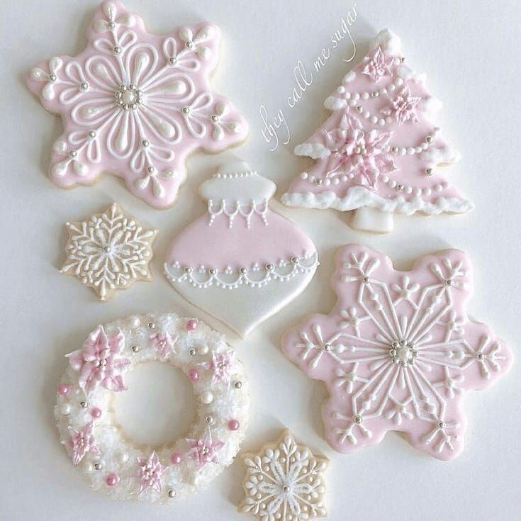 decorated cookies are arranged in the shape of christmas trees and snowflakes, on a white surface