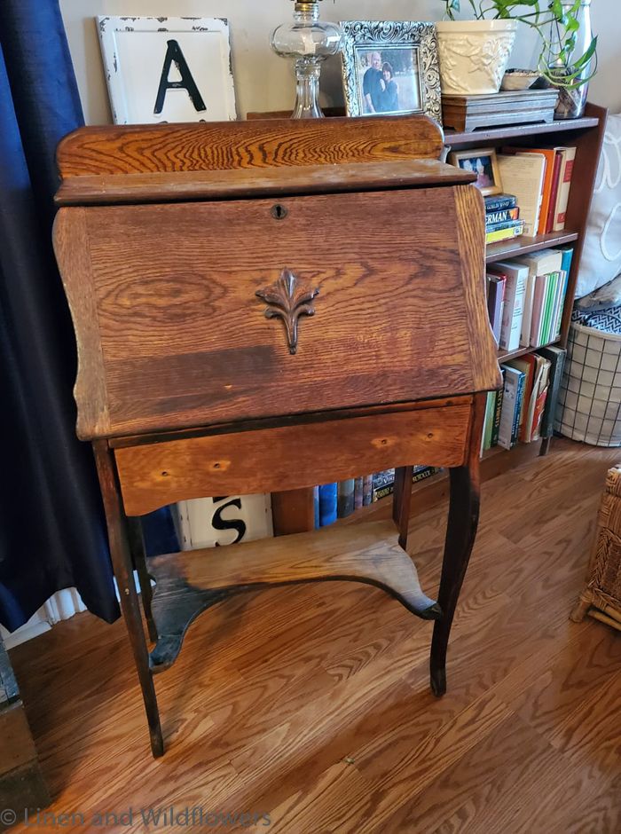 an old fashioned wooden cabinet sitting on top of a hard wood floor next to a bookshelf