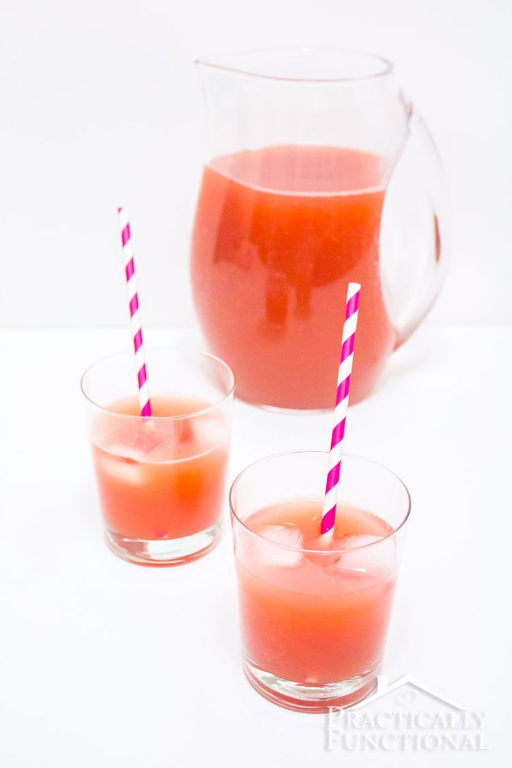 two glasses filled with orange juice next to a pitcher and cup full of liquid on a white surface