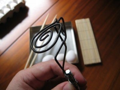 a person holding an electric guitar string in front of a wooden box with white balls on it