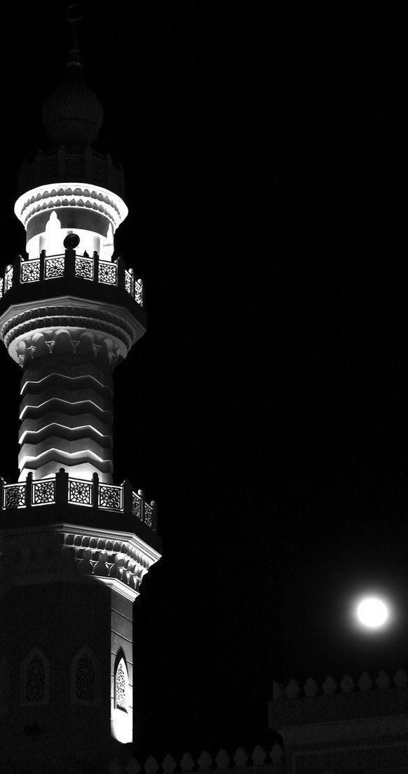 a tall tower with a clock on it's side lit up at night time