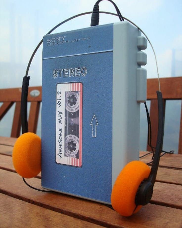 an old cassette player with headphones attached to it sitting on top of a wooden table