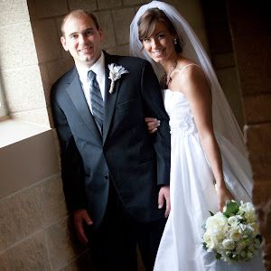 a bride and groom pose for a photo in front of a window at their wedding