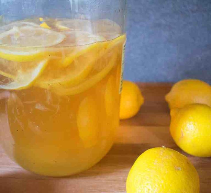 a pitcher filled with lemonade sitting on top of a wooden cutting board