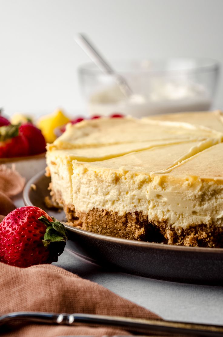 a cheesecake on a plate with strawberries and other dessert items in the background